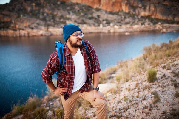 A tired hiker pauses for breath while climbing up a mountain with lake view. High quality photo