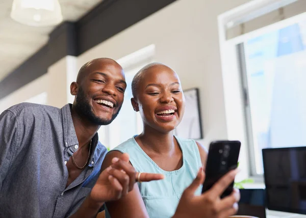 Two Black colleagues watch a funny video on cellphone point and laugh. High quality photo
