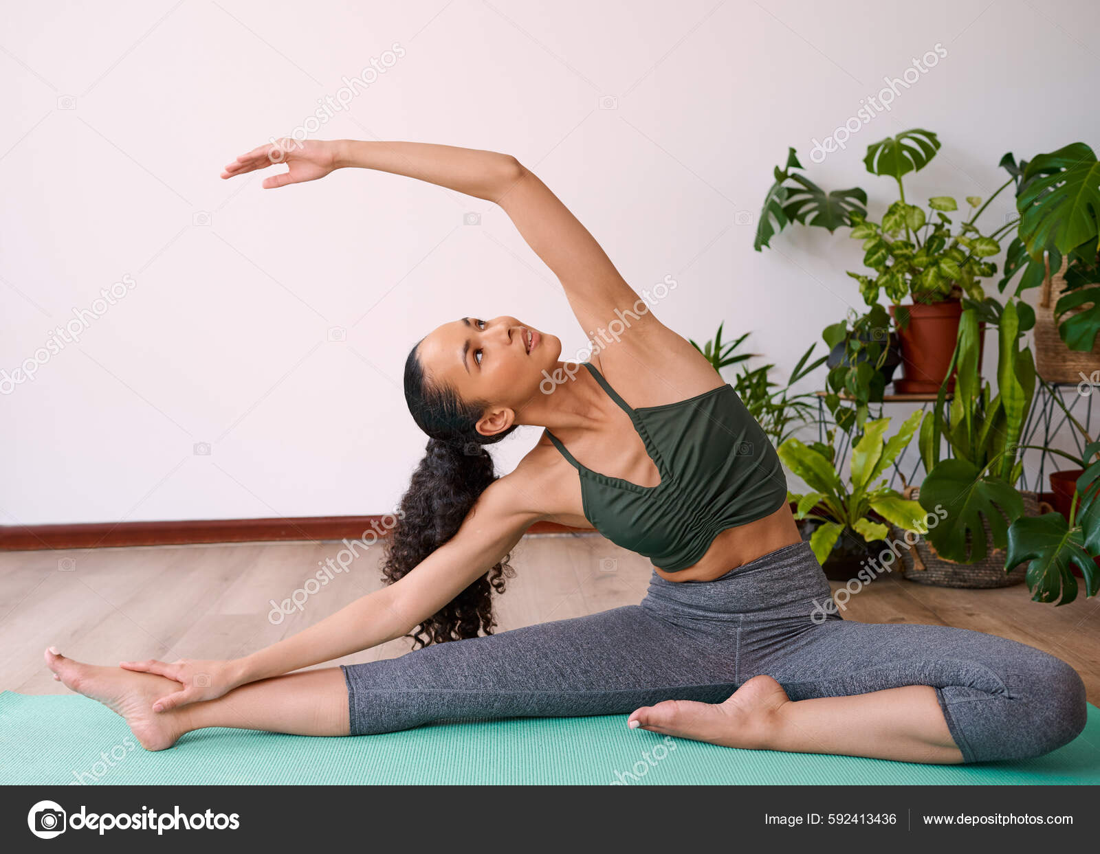 Young Multi Ethnic Woman Reaches Overhead Seated Side Stretch Yoga fotos,  imagens de © MeekoMedia #592413436