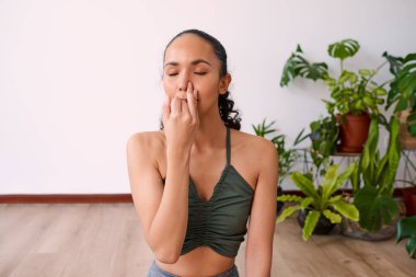 A young woman meditates with alternate nostril breathing to calm anxiety. High quality photo clipart