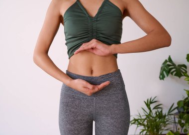 Close up of a young multi-ethnic womans stomach cupped by her hands. High quality photo