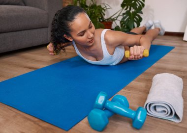 A young multi-ethnic woman uses weights during floor workout. High quality photo