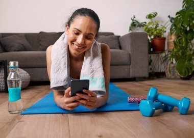 A young multi-ethnic woman tracks her exercise on fitness app after workout. High quality photo