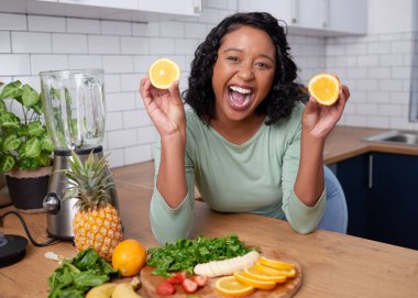 A young multi-ethnic woman poses with oranges and laughs while making smoothie. High quality photo