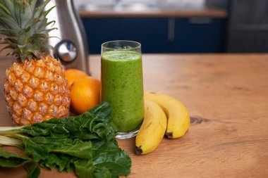 Close up still life of whole fruit and freshly made green smoothie in kitchen. High quality photo