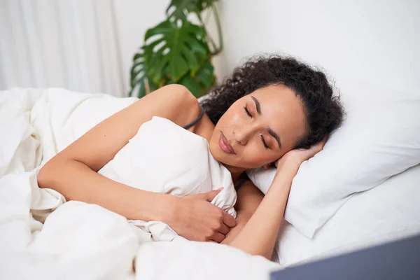 A young multi-ethnic woman sleeps in bed comfortably . High quality photo