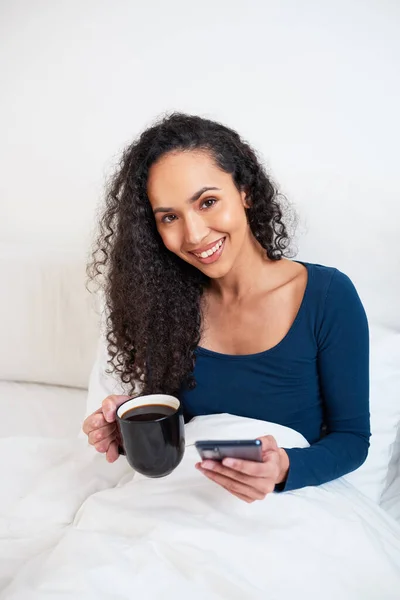 Μια Νεαρή Πολυεθνική Γυναίκα Πίνει Καφέ Στο Κρεβάτι Ενώ Ξυπνά — Φωτογραφία Αρχείου