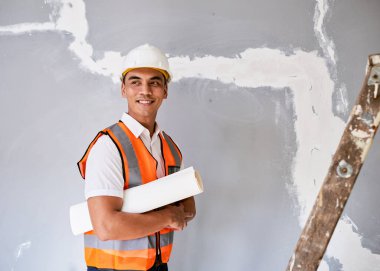 Çekici bir Asyalı inşaat işçisi kolunun altında bina planlarını tutuyor. Yüksek kalite fotoğraf