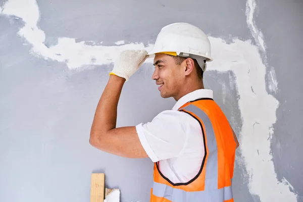 Portrait of an Asian construction worker tipping his hat facing left. High quality photo