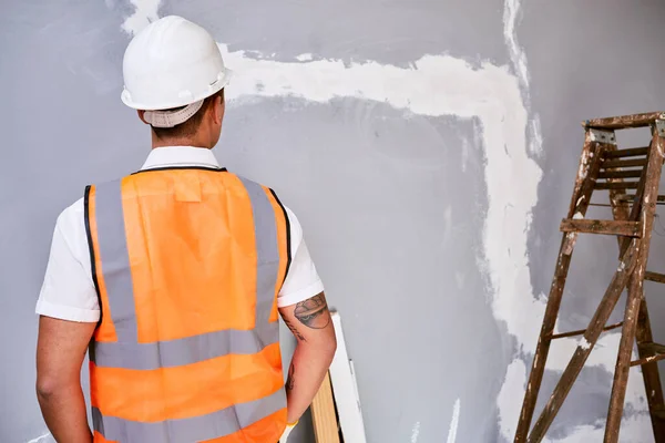 The back of a construction worker in uniform as he faces work in progress. High quality photo