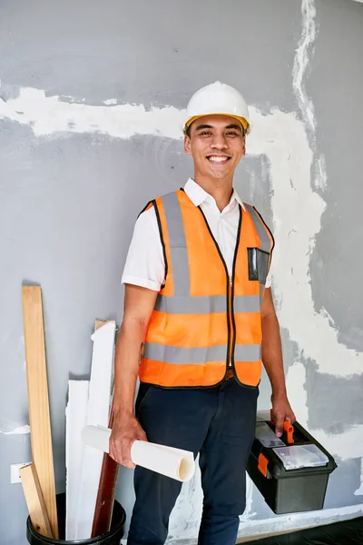 Portrait of a construction supervisor on site with building plans and toolbox. High quality photo