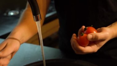 Adam mutfakta kırmızı kiraz domateslerini yıkıyor.