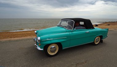 FELIXSTOWE, SUFFOLK, ENGLAND - MAY 01, 2022:  Classic  Skoda Felicia Convertible being driven on seafront promenade beach and sea in the background.