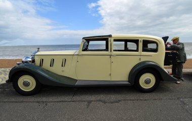 FELIXSTOWE, SUFFOLK, ENGLAND - MAYIS 05, 2019: Güzel Krem Renkli Klasik Rolls Royce Otomobili deniz kenarında arka planda insan gramofonu, plaj ve denizle çalışan bir araç.