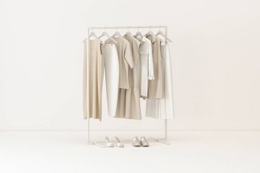 Giysiler arka planda, raf arka planda. Tarafsız bej rengi bir askıda asılı kıyafet koleksiyonu. 3D görüntüleme, depolama ve yatak odası konsepti