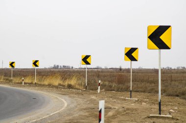 Yol üzerinde siyah oklar olan sarı işaretler