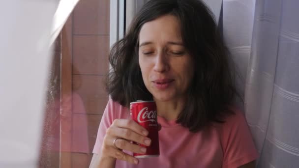 布鲁内特的妇女画像打开了一个可乐罐 边站在窗边边边边喝碳酸饮料 — 图库视频影像