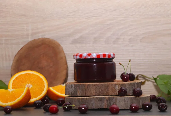 Homemade cherry and orange jam. Jar of jam, cherries, oranges, tree slices