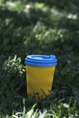 Bir fincan sıcak kahve, çay, parkta kakao çimlerin üzerinde Ukrayna bayrağı renginde.