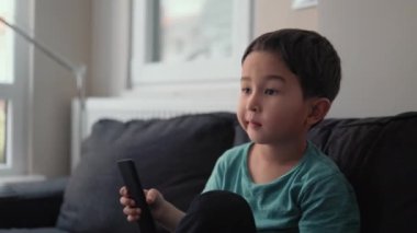 Evdeki TV 'de uzaktan kumandalı küçük şirin çocuk kanal değiştiriyor.
