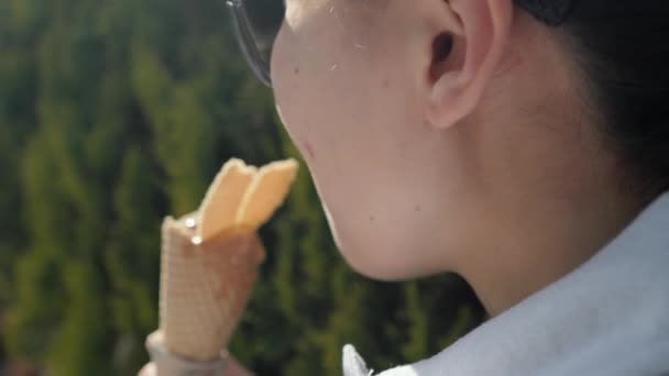 Woman bites a cookie on top of the ice cream cone on sunny hot day. — Stock Video