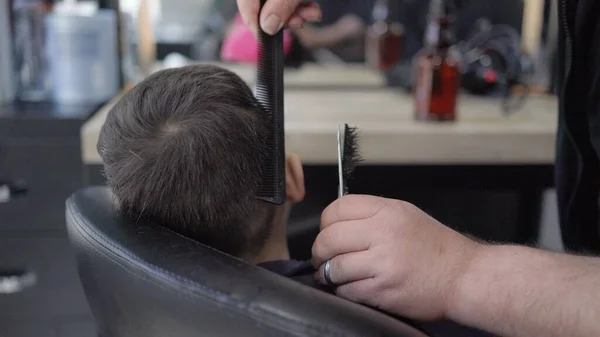 Перукар розрізає маленьких хлопчиків волосся ножицями. Дитина в салоні — стокове фото
