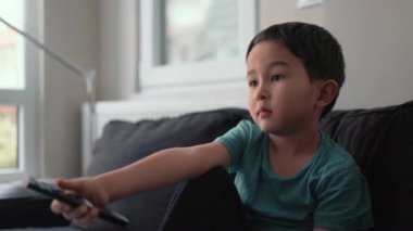 Evdeki TV 'de uzaktan kumandalı küçük şirin çocuk kanal değiştiriyor.
