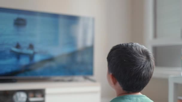 Back view of little boy watching movie on TV at home — Video Stock