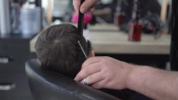 The hairdresser cuts the little boys hair with scissors. Child in salon — 비디오