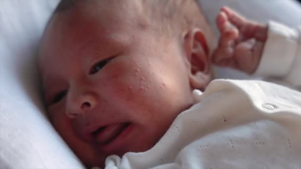 Közelről láthatjuk a síró újszülöttet fehérben. A baba felhívja a szülőket, hogy megetesse. A baba mozgatja a karját és a lábát. — Stock videók