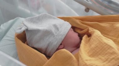 Yeni doğan bebek hastanede doğumdan sonra karyolada uyur.