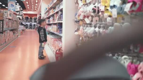 Asian preschooler looking for toys in supermarket while his little brother is in stroller — Vídeos de Stock