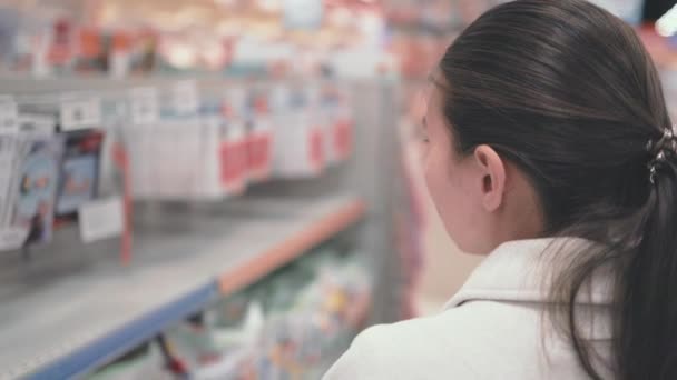 Rear view of woman in supermarket searching for goods — стоковое видео