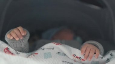 Close up of babies hands while he is sleeping in stroller