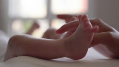 Mother holds newborn babys legs. Happy motherhood, parenthood