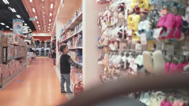 Asian preschooler looking for toys in supermarket while his little brother is sleeping in stroller — Vídeos de Stock