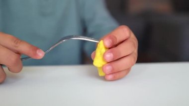 Küçük ellerin yakın çekim görüntüsü çatal kullanarak bir figür yontuyor