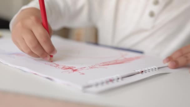 Γκρο πλαν άποψη των μικρών χεριών σχέδιο με κόκκινο στυλό σε λευκό χαρτί. — Αρχείο Βίντεο