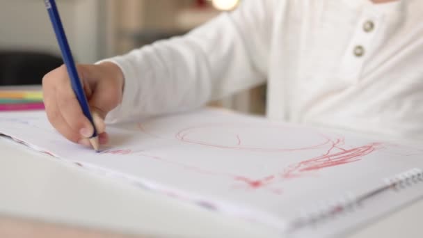 Vista ravvicinata di piccole mani che disegnano con penna blu su un foglio bianco. — Video Stock