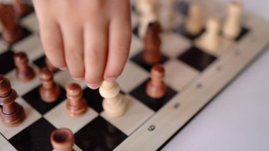 Satranç tahtasındaki satranç figürünü hareket ettiren küçük ellerin yakın plan görüntüsü