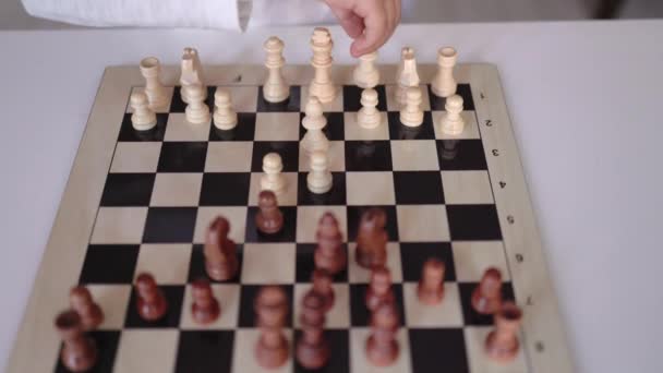 Крупный план маленьких ручек, перемещающих шахматную фигуру на шахматной доске — стоковое видео