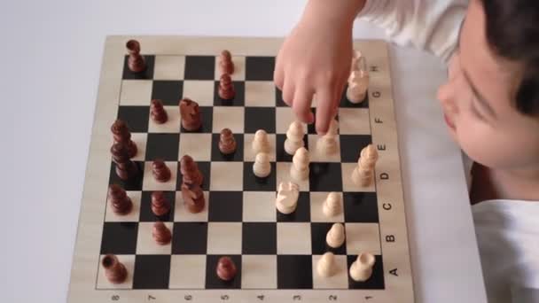 Little boy moving a chess figure on a chessboard — Stockvideo