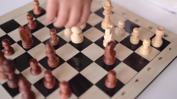 Крупный план маленьких ручек, перемещающих шахматную фигуру на шахматной доске — стоковое видео