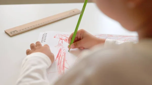 Visão traseira do desenho pré-escolar com caneta vermelha em um livro branco. — Fotografia de Stock