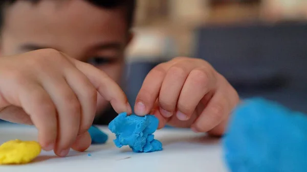 Vue rapprochée de la petite maternelle asiatique jouant avec de l'argile bleue et jaune sur la table — Photo