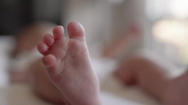 Cute asian baby lies and looking to window. Close up legs view