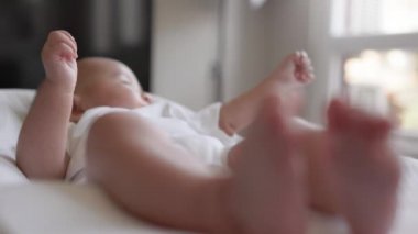 Cute asian baby lies and looking to window. Close up view