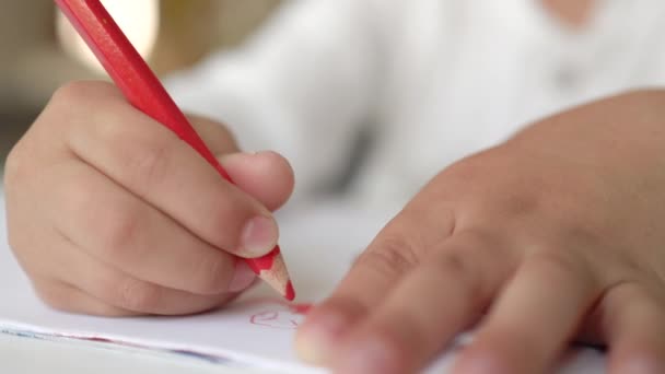 Close-up widok małych rąk rysunek z czerwonym piórem na białym papierze. — Wideo stockowe