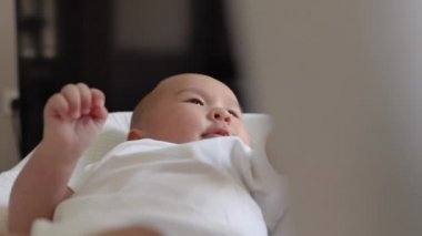 Beyazlar içinde şirin bir bebek, annesinin elini tutuyor. 