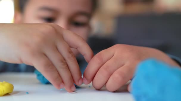 Masanın üzerinde mavi ve sarı kille oynayan küçük Asyalı anaokulu öğrencisinin yakın çekim görüntüsü — Stok video